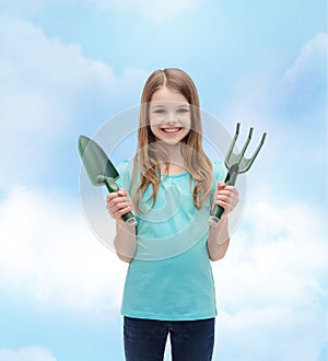 Smiling little girl with rake and scoop