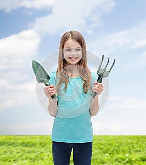 Smiling little girl with rake and scoop