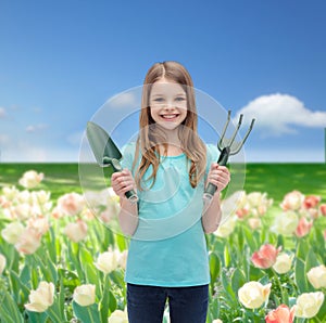 Smiling little girl with rake and scoop