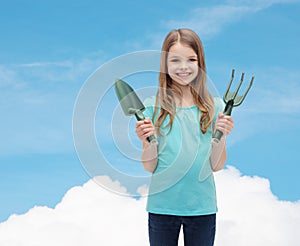 Smiling little girl with rake and scoop