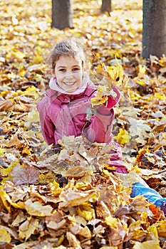 Smiling little girl in red jacket sits in drift of photo