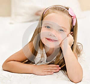 Smiling little girl resting on the bed