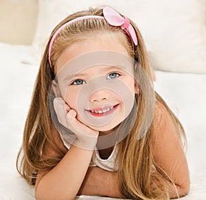 Smiling little girl resting on the bed