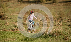 Smiling little girl riding a bike turned away