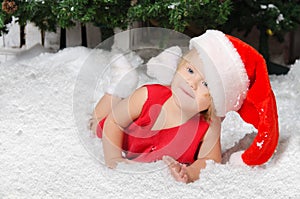 Smiling little girl in santa costume on snow