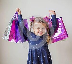 Smiling little girl with shopping bags with gifts.