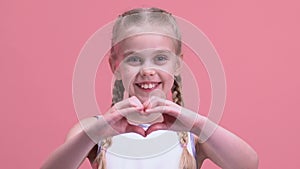 Smiling little girl showing heart gesture, charity, orphan children adoption