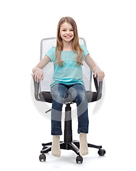 Smiling little girl sitting in big office chair