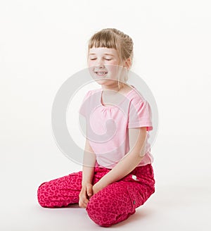 Smiling little girl sitting on the floor with closed eyes