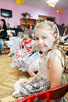 Smiling little girl sitting in kindergarten class looking at camera