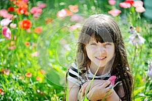 Smiling little girl sitting on poppy field