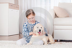 Smiling little girl sitting with retriever puppy