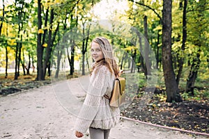 Smiling little girl stand is walking in the forest at autumn day.