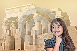 Smiling little girl is standing in front of Kom Ombo temple.