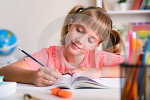 Smiling little girl studying in her room at home