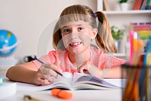 Smiling little girl studying in her room at home looking