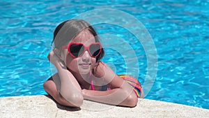 Smiling little girl in sunglasses in pool on sunny day. Childhood, valentine's day summer concept