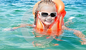 Smiling little girl swimming with life jacket