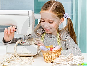 Smiling little girl at the table with sewing