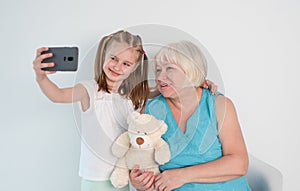 Smiling little girl taking selfie with grandmother