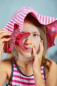 Smiling little girl wearing pink hat holding starfish