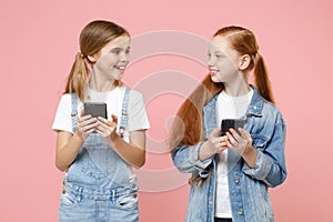 Smiling little kids girls 12-13 years old in denim clothes isolated on pink background. Childhood lifestyle concept