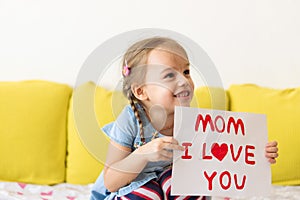 smiling little preschool child girl holding greeting card for Happy Mother's Day with drawn red heart. Loving