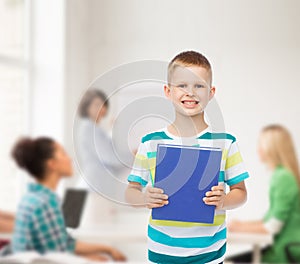 Smiling little student boy with blue book