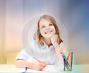 Smiling little student girl drawing at school