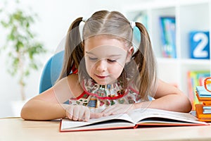 Smiling little student girl reading book