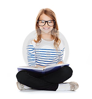 Smiling little student girl sitting on the floor