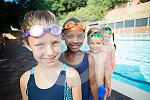 Smiling little swimmers standing at poolside