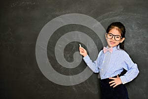 Smiling little teacher standing in blackboard