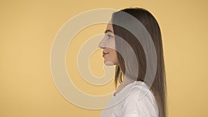 Smiling long-haired woman middle age on yellow background in studio. Middleweight woman in basic white t-shirt