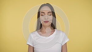 Smiling long-haired woman middle age on yellow background in studio. Middleweight woman in basic white t-shirt