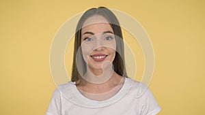 Smiling long-haired woman middle age on yellow background in studio. Middleweight woman in basic white t-shirt