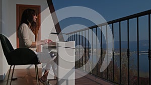 Smiling long-haired woman pianist playing on electric keyboard on verandah