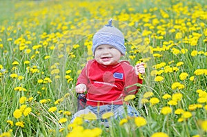 Smiling lovely baby against dandelions meadow