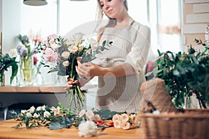 Smiling lovely young woman florist arranging plants in flower shop