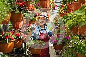 Smiling lovely young woman florist arranging plants in flower shop. The hobby has grown into a small business.