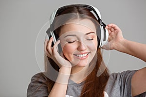 Smiling lovely young woman listening to music using headphones
