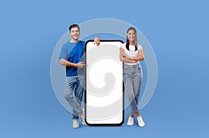 Smiling Lovers Presenting Blank Mobile Phone Screen on Blue Background