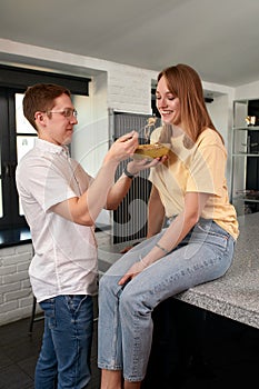 Smiling loving husband feeding wife, young couple enjoying tender moment, romantic date, having fun, eating japanese