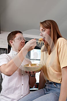 Smiling loving husband feeding wife, young couple enjoying tender moment, romantic date, having fun, eating japanese