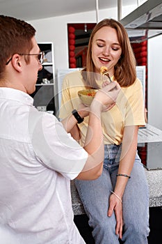 Smiling loving husband feeding wife, young couple enjoying tender moment, romantic date, having fun, eating japanese