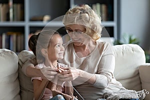 Smiling loving mature grandmother teaching little granddaughter knitting