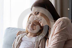 Smiling loving mom and small daughter relax cuddle