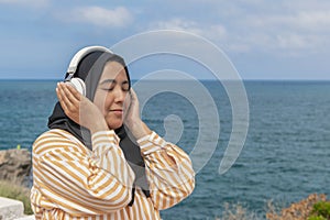 Smiling maghrebi woman with hijab listening to music