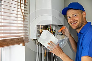 Smiling maintenance and repair service engineer working with house gas heating boiler