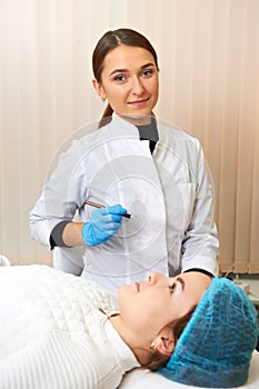 Smiling make-up wizard makes eyebrow correction procedure.